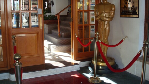 L’entrée d’un hôtel, avec un tapis rouge, une statue dorée et un escalier menant à l’étage supérieur.