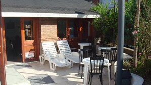 Un espace extérieur abrité avec des fauteuils et des tables, un bâtiment en briques et un lampadaire.