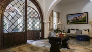 Un salon spacieux avec une grande porte en arc, un canapé, une table basse et un tableau accroché au mur.