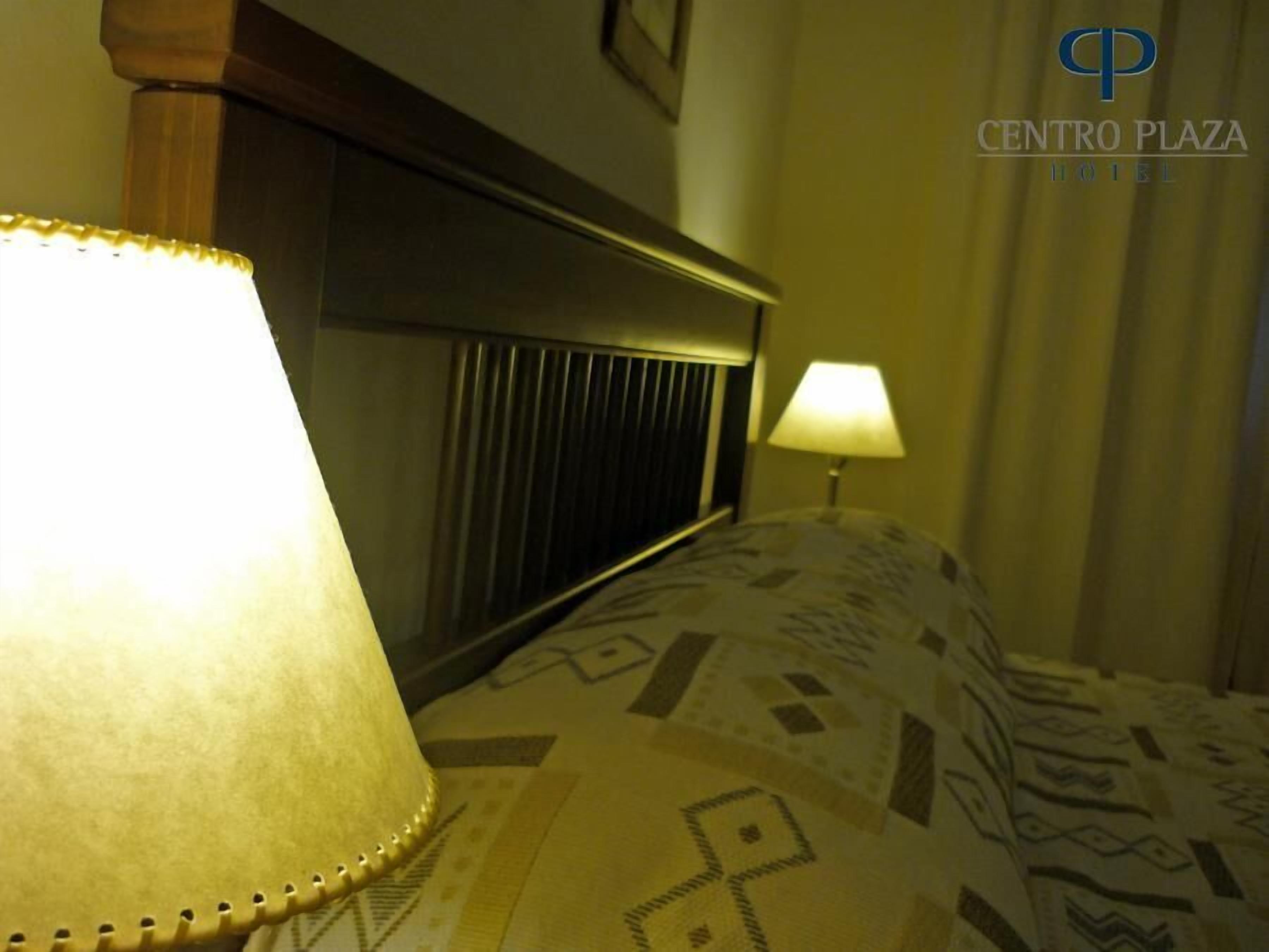 Una habitación de hotel con una cama, una lámpara de noche y un cabecero.