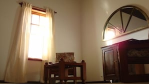 A room with a wooden chair, a cabinet, and a window with curtains. - Yr Hen Ffordd (Gaiman)