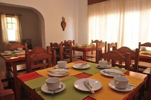 Un comedor con varias mesas y sillas, cada conjunto con platos, tazas y cubiertos.