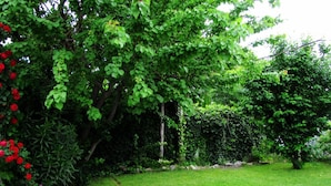 A lush garden with a variety of trees and shrubs, a well-maintained lawn, and a stone pathway. - Yr Hen Ffordd (Gaiman)