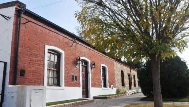 A two-story brick building with white trim, a front entrance, and a small porch area. - Yr Hen Ffordd (Gaiman)