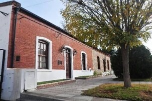 Un edificio de ladrillo de dos pisos con detalles blancos, una entrada principal y un pequeño porche.