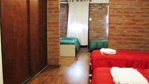 A room with two beds, a wooden floor, and brick walls. - Yr Hen Ffordd (Gaiman)
