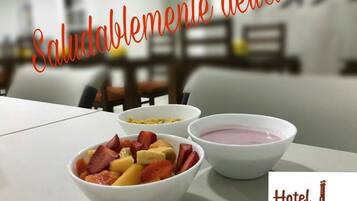 Een ontbijttafel met schalen fruit en yoghurt, en het logo van Hotel El Faro Buga.