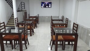A dining area with multiple tables and chairs, a staircase, and a television mounted on the wall. - Hotel El Faro Buga (Guadalajara de Buga)