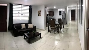 A living room with a sofa, coffee table, and dining area with chairs and a table. - Hotel El Faro Buga (Guadalajara de Buga)