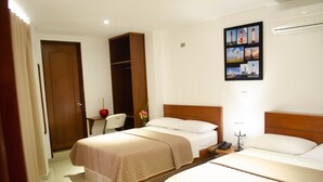 A hotel room with two beds, a wooden wardrobe, a desk with a lamp, and a wall-mounted photo collage. - Hotel El Faro Buga (Guadalajara de Buga)