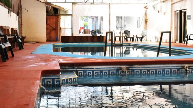 An indoor swimming pool with a tiled floor and a clear ceiling structure. - Hotel Savoia (San Clemente)