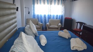 A neatly made bed with pillows and towels, two armchairs, a small table with a red tray, and a wooden chair. - Hotel Savoia (San Clemente)