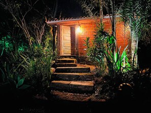 A brick building with a wooden door and steps leading up to it, surrounded by vegetation. - Pousada Candonga Da Serra Hotel (Tiradentes)