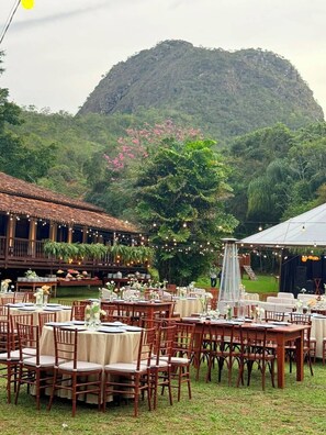 An outdoor dining area with tables and chairs, surrounded by lush greenery and a mountain backdrop. - Pousada Candonga Da Serra Hotel (Tiradentes)