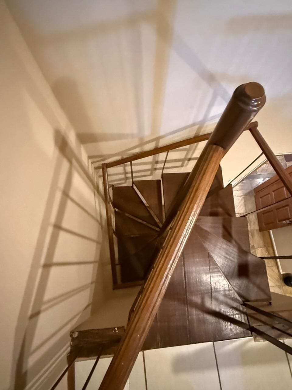 A spiral staircase with wooden handrails and a metal railing.