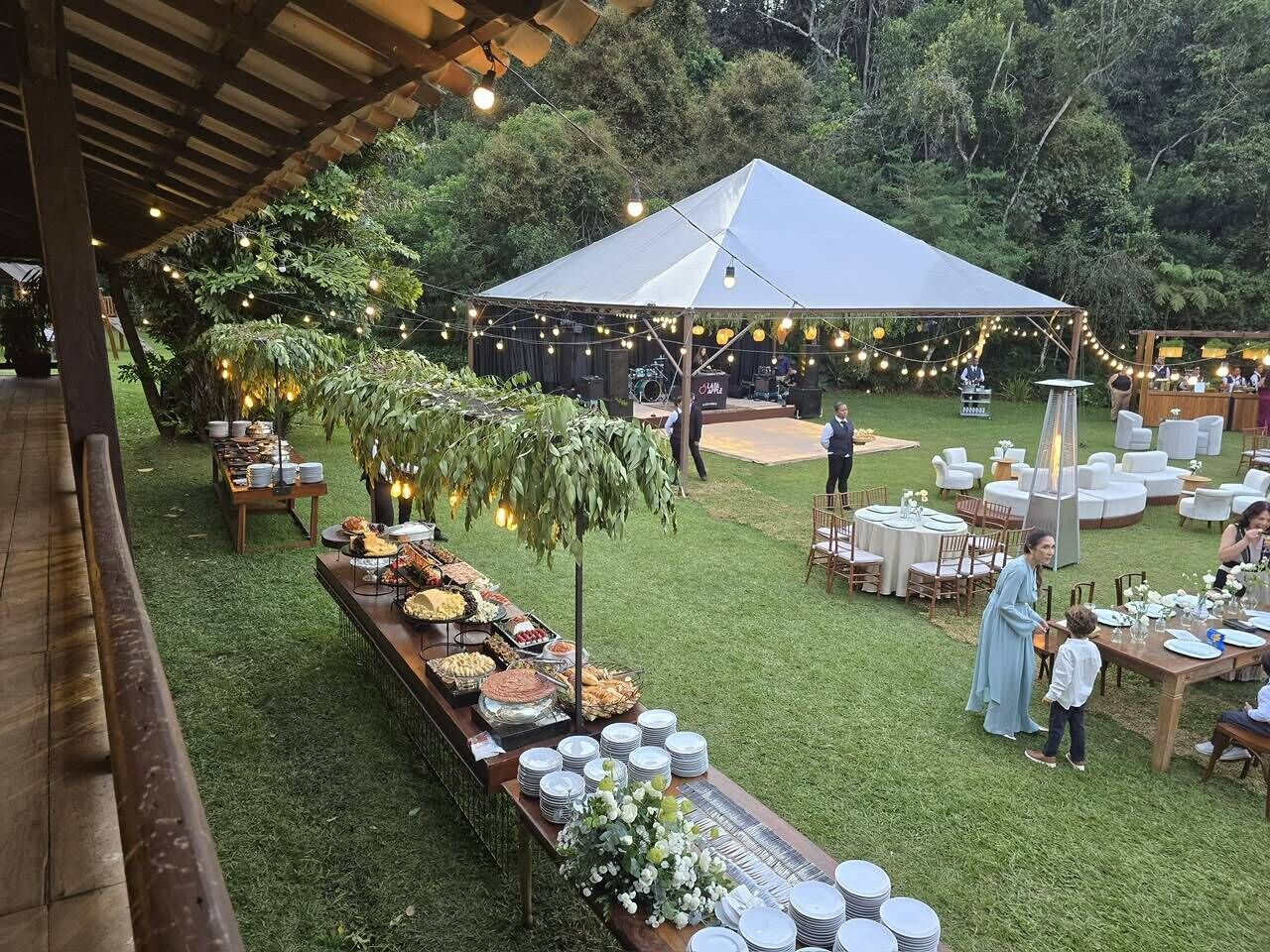 An outdoor event with a tent, tables set for dining, and a buffet with various food items.