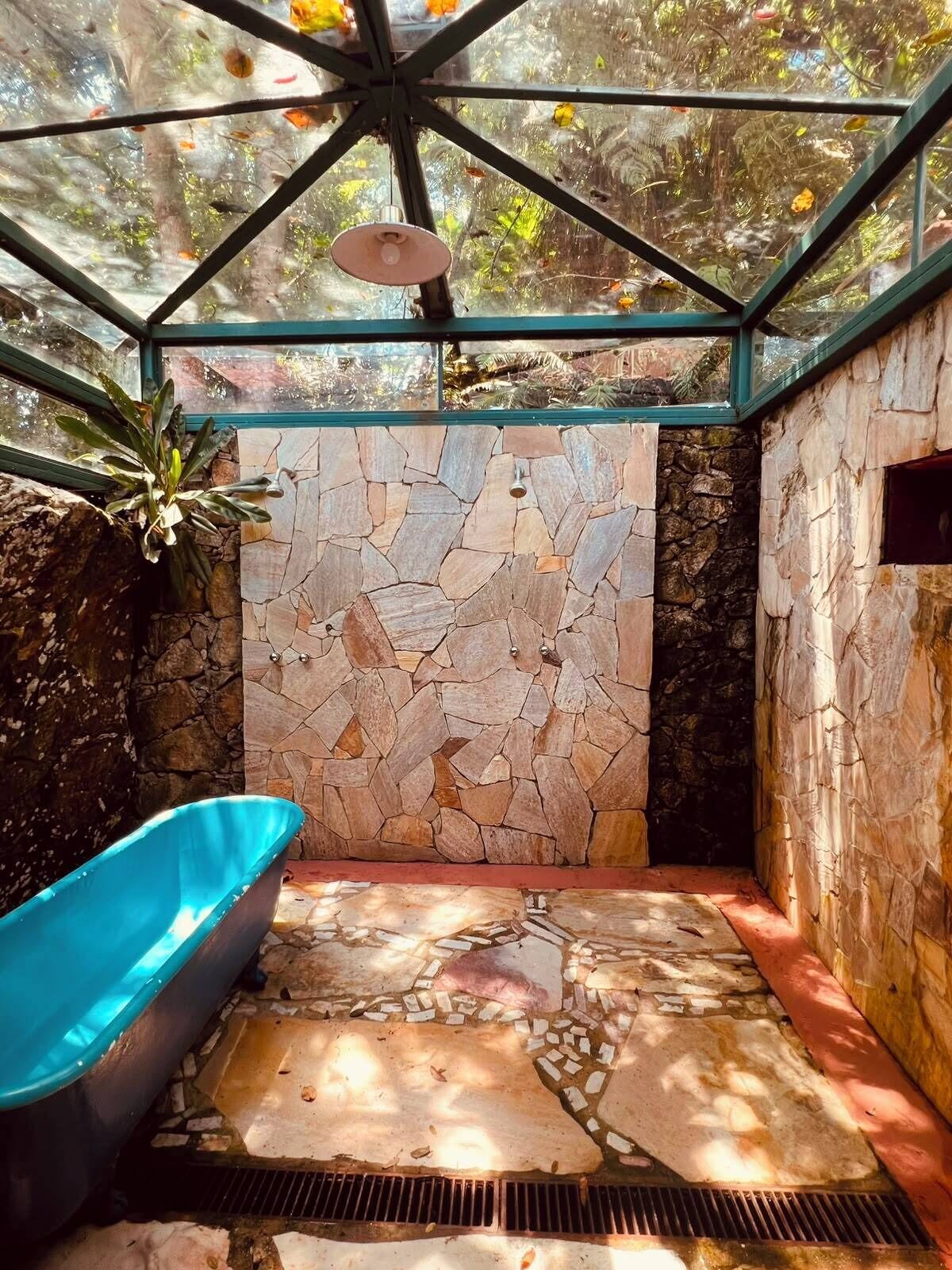 A bathroom with a stone wall, a blue bathtub, and a skylight.