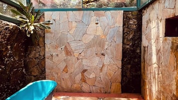 Un baño con pared de piedra, bañera azul y tragaluz.