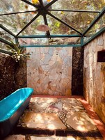 A bathroom with a stone wall, a blue bathtub, and a skylight.