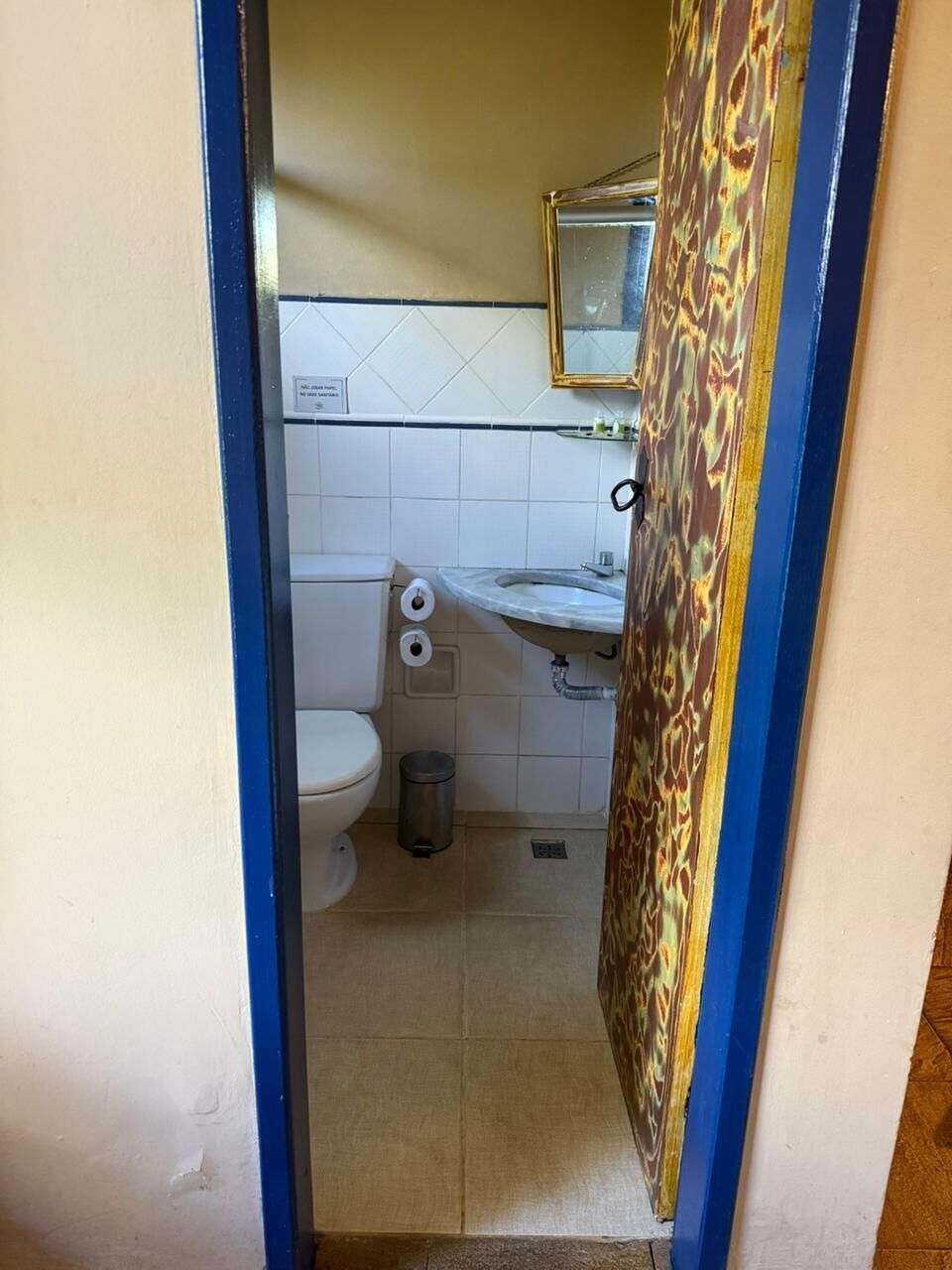 A small bathroom with a toilet, sink, and a mirror above the sink.