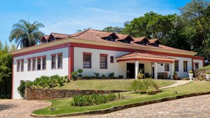 Un edificio de dos pisos con fachada roja y blanca, un patio cubierto y una entrada empedrada con piedra.