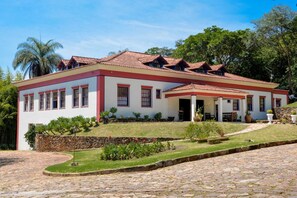 A two-story building with a red and white facade, a covered patio area, and a stone-paved entrance. - Pousada Candonga Da Serra Hotel (Tiradentes)