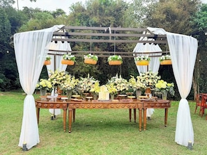Montaje para un evento al aire libre con una mesa decorada con arreglos florales y una estructura de toldo.