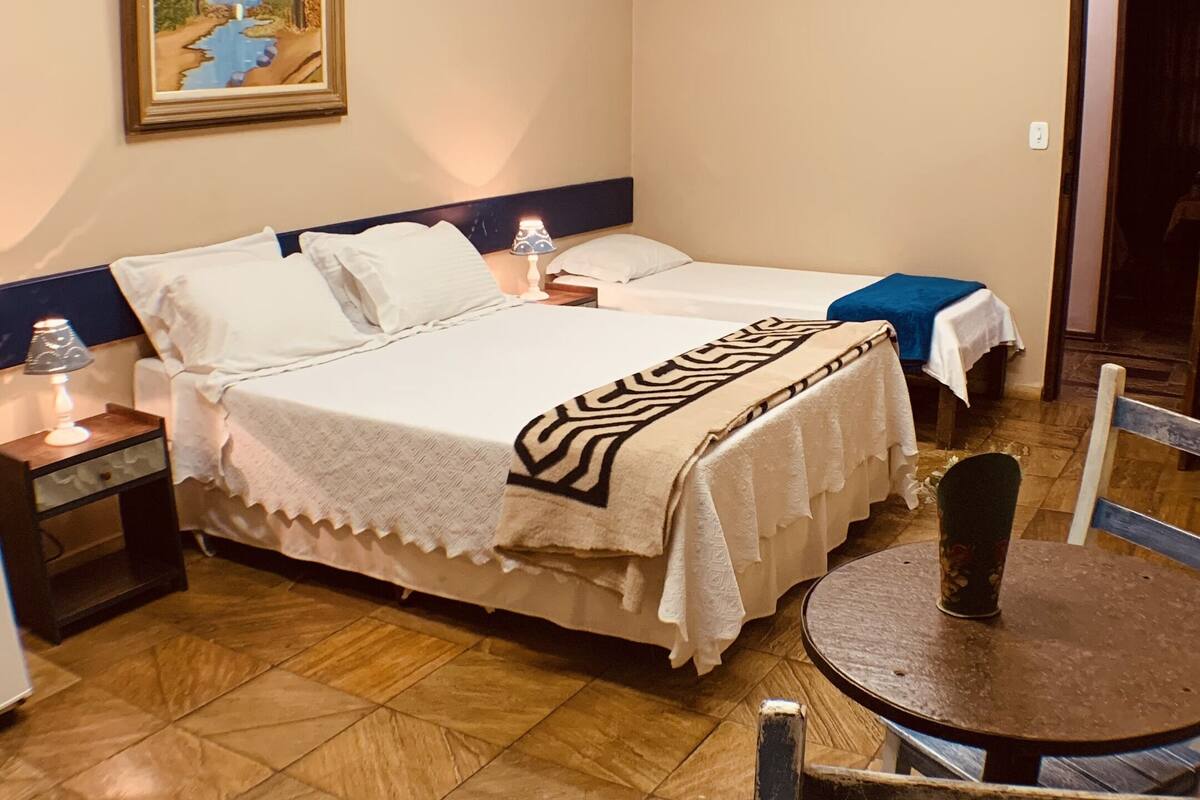 A hotel room with a bed, bedside tables, a lamp, a chair, and a painting on the wall.