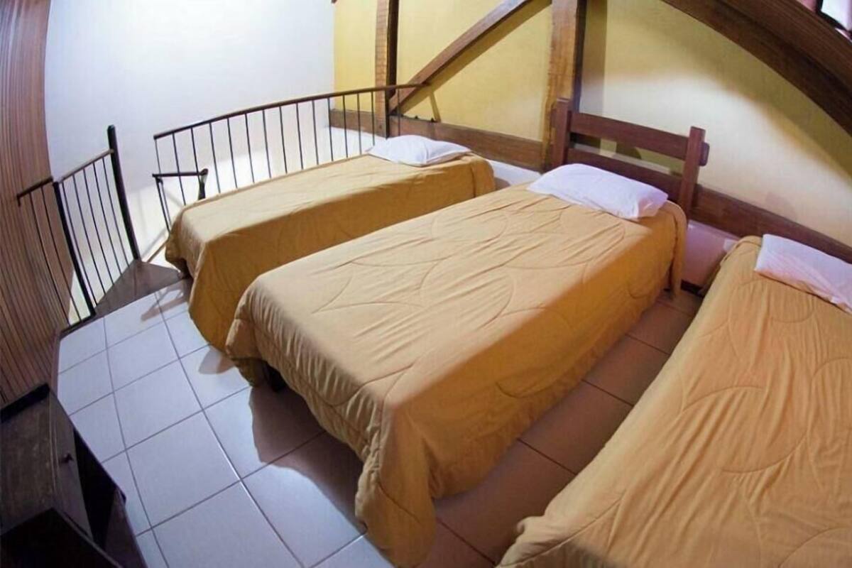 A room with two beds, a wooden headboard, a tiled floor, and a metal railing.