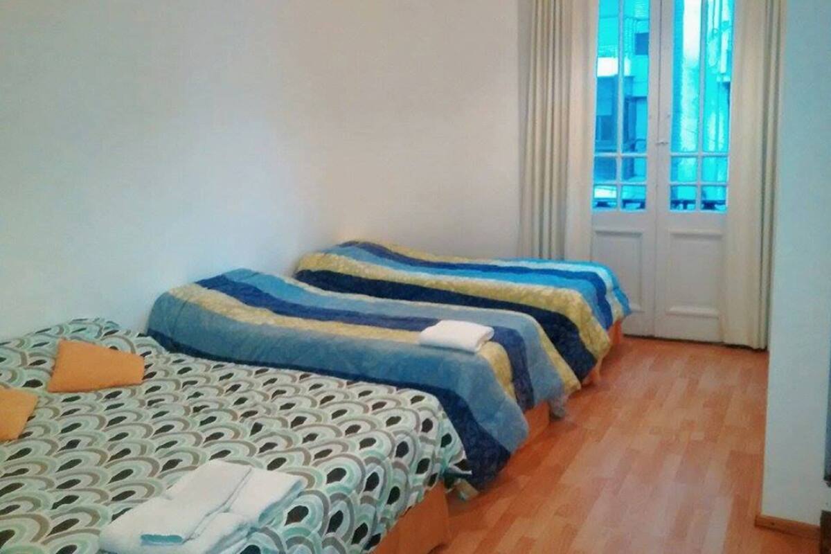 Une chambre d’hôtel avec deux lits, une couvre-lit à motifs et une vue sur l’extérieur grâce à une porte dotée de panneaux de verre.