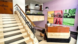 A hotel reception area with a staircase, a reception desk, and a wall with colorful artwork. - Altea Hotel de Rosario (Rosario)