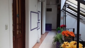 A corridor with a wooden door, a wall-mounted light switch, a potted plant, and a staircase. - Altea Hotel de Rosario (Rosario)