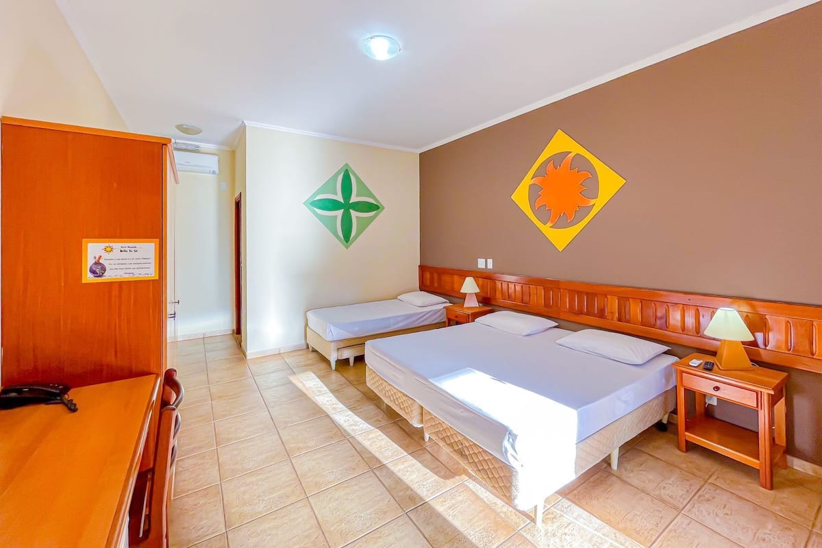 A hotel room with two beds, a wooden table, and a desk with a lamp.