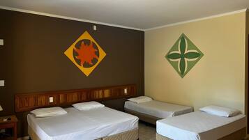 A hotel room with two single beds, a wooden headboard, and a wall with two decorative symbols.