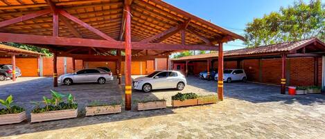 Un estacionamiento techado con varios autos estacionados bajo una estructura de madera.