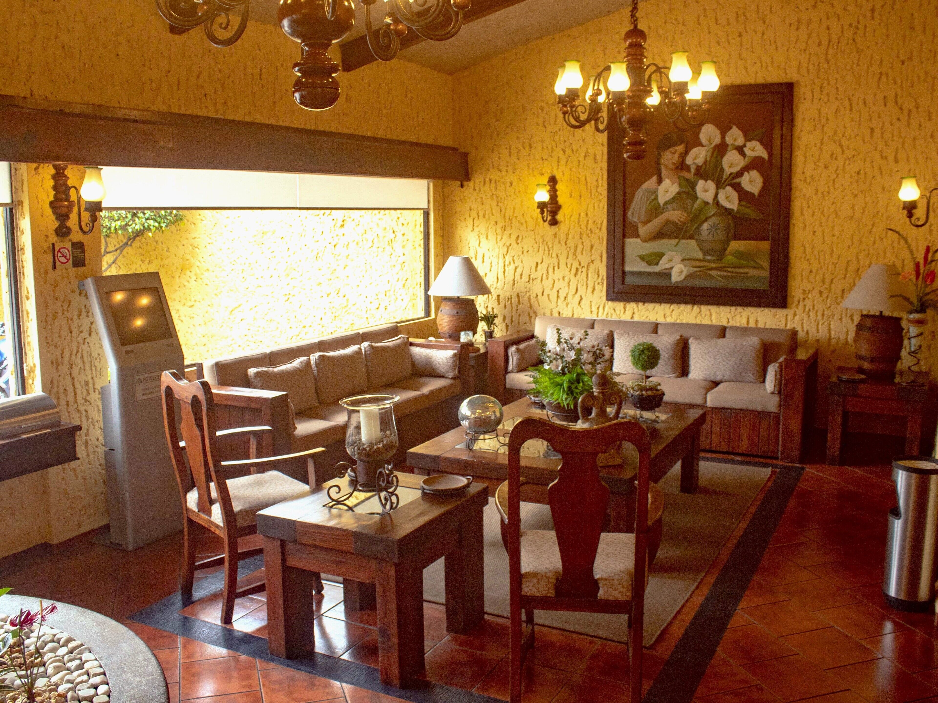 Una sala acogedora con sofá, mesa de comedor, sillas y una mesita de centro. Hay un cuadro en la pared, una lámpara y una ventana con vistas.