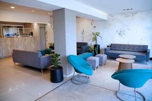 Relax in our inviting lobby, featuring a comfortable seating area with a sofa and armchair, a coffee table, and a unique architectural pillar.