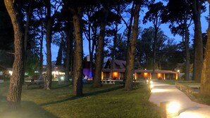 A lodge with a rustic design, featuring a central building surrounded by trees, a paved walkway, and outdoor seating areas.