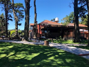 A rustic building with a red-tiled roof, surrounded by tall trees and a well-maintained lawn. - Hotel Villa Santa Maiani (Mar del Plata)