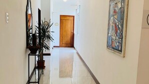A hallway with a wooden door at the end, a potted plant, and a framed abstract painting on the wall. - Hotel Casa del Sol (Managua)