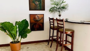 A corner room with a tiled floor, two wooden chairs, a potted plant, and two abstract paintings on the wall. - Hotel Casa del Sol (Managua)