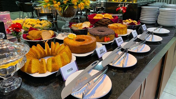 Ein Buffet mit verschiedenen Speisen und einem Schild mit der Aufschrift 'Bolo de Canela'.