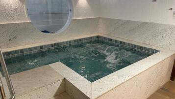 Relax in a serene space with a hot tub and a circular window above.