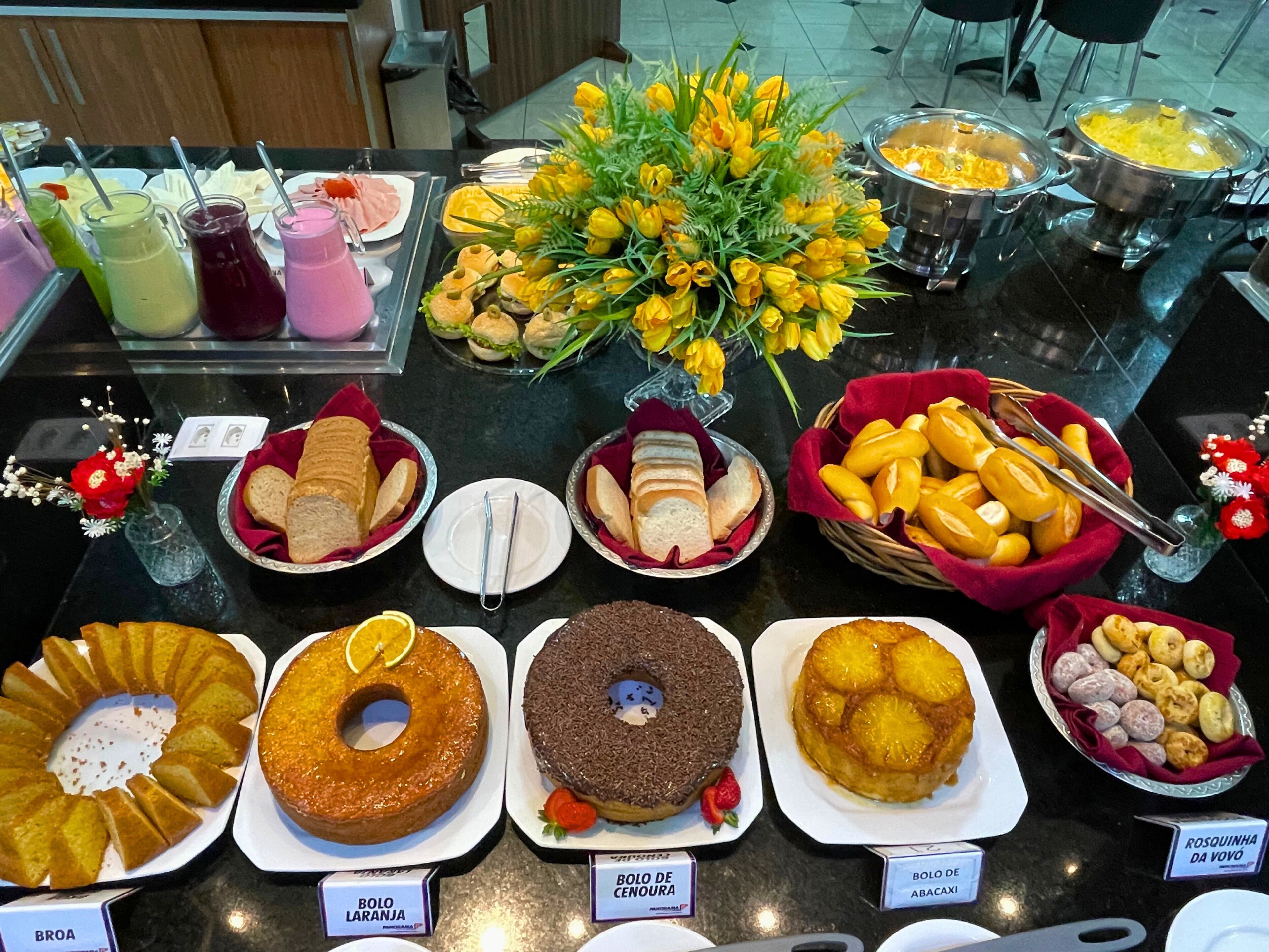 Une table de buffet proposant divers plats, notamment des gâteaux, du pain et des fruits.