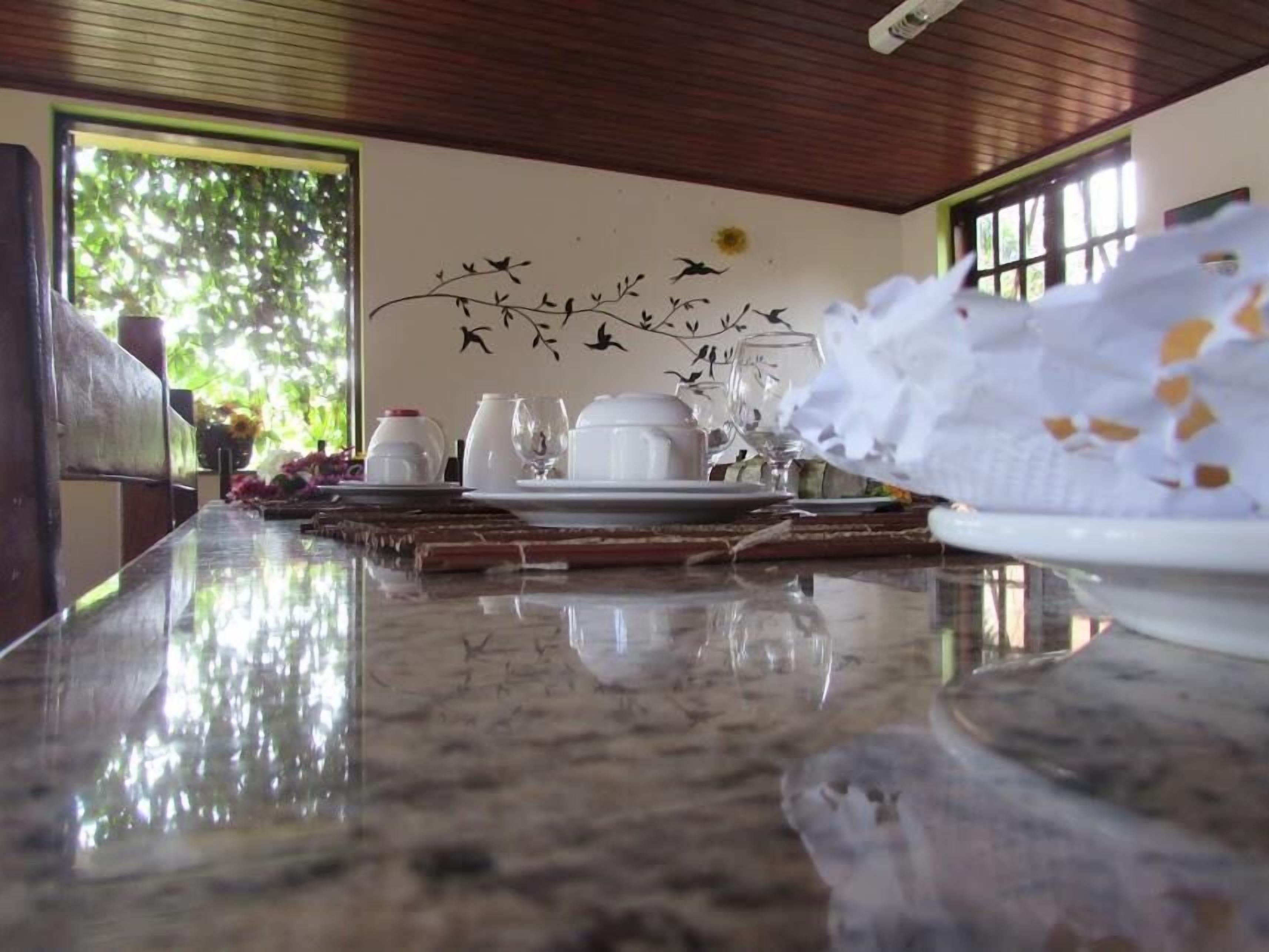 A dining area with a polished marble table, white tableware, and a wall mural of birds.