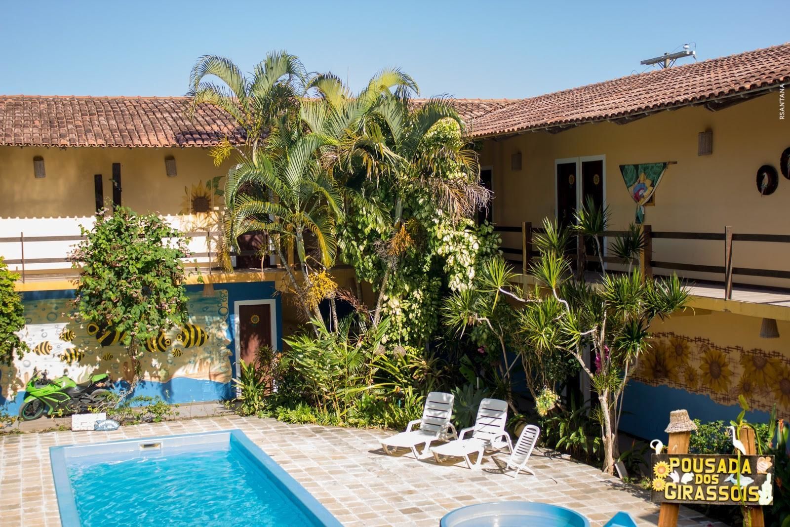 Un área de piscina con tumbonas, un techo de azulejos y abundante vegetación.