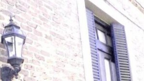 A building facade with a brick wall and a window with shutters. - Ñanderoga (Corrientes)