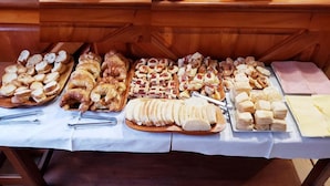 Une table de buffet proposant divers aliments, notamment du pain, des pâtisseries et de la viande.