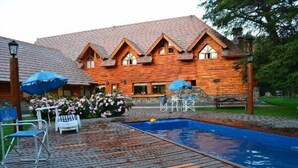 Une cabane en bois avec une piscine, un espace salon extérieur et un jardin.