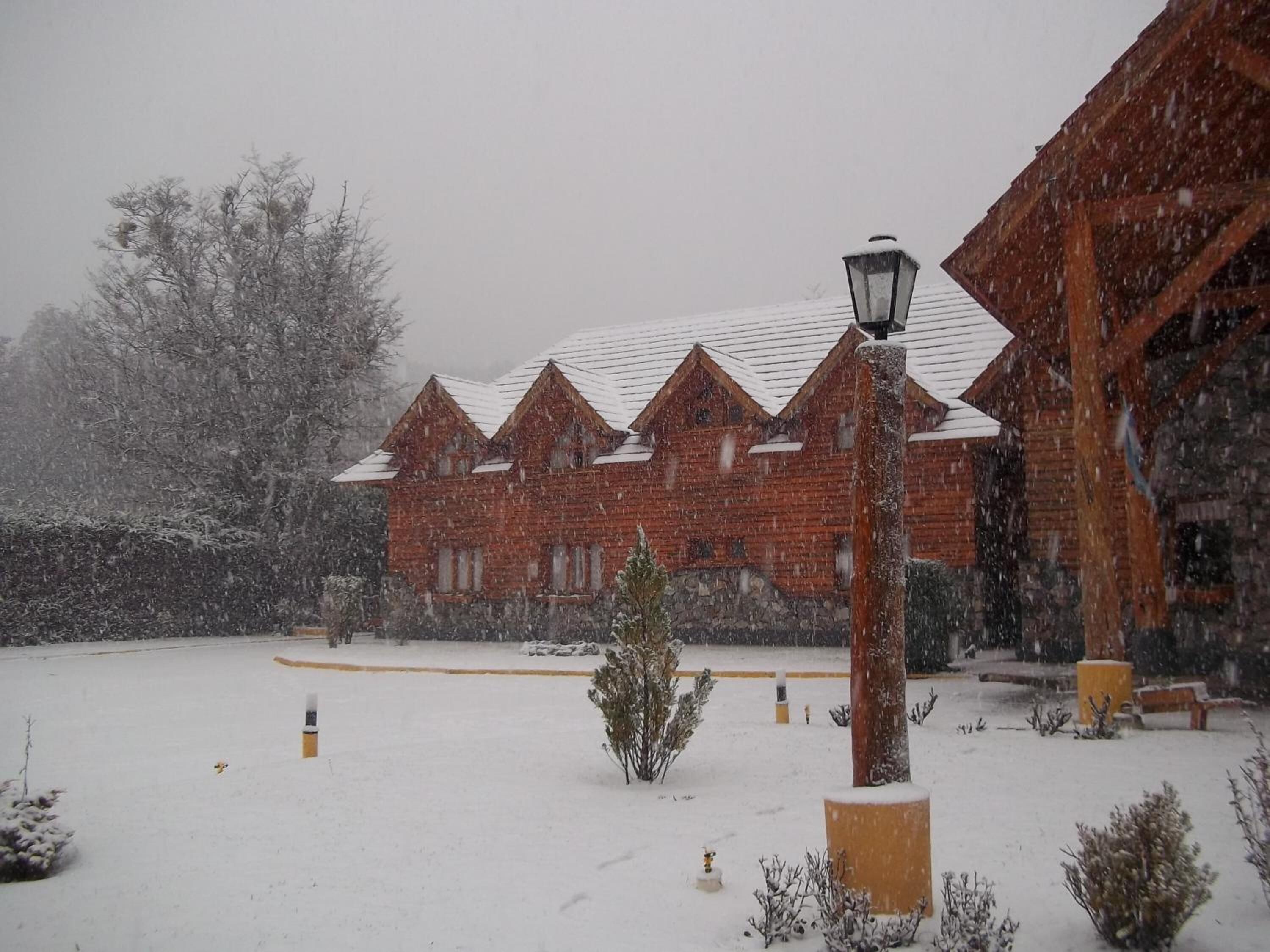Een bakstenen gebouw met een met sneeuw bedekte dak en een lantaarn ervoor.